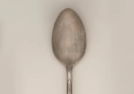 Metalowa lub srebrna łyżeczka z uchwytem zdobionym na końcu.