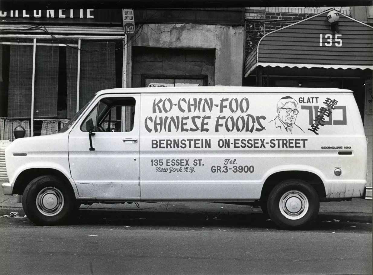 Kolorowa fotografia. Biała furgonetka z czarnym napisem: Ko-Chin-Foo, Chinese Foods.