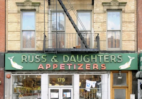 Kolorowa fotografia budynku. Na parterze wejście do restauracji. Powyżej szyld: Russ & Daughters. Appetizers, czyli przekąski.