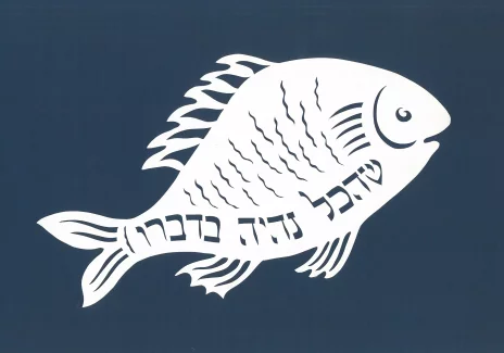 Wycinanka w kształcie ryby z widocznym na jej boku napisem w języku hebrajskim.