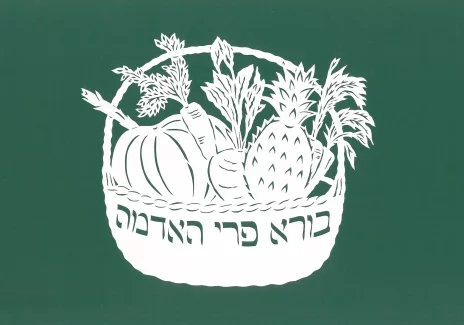 Wycinanka w kształcie koszyka z warzywami. Z boku koszyka widoczny napis w języku hebrajskim.