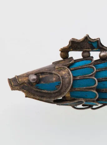 Silver fish with blue scales and tail. It resembles a brooch.