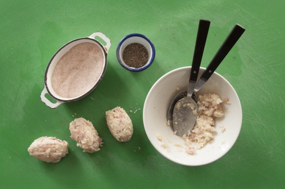 Osoba przygotowująca potrawę formuje pulpety za pomocą dwóch łyżek. Obok znajduje się miska z jasną pulpą, obok dwie miseczki: jedna z pieprzem, a druga z solą himalajską.