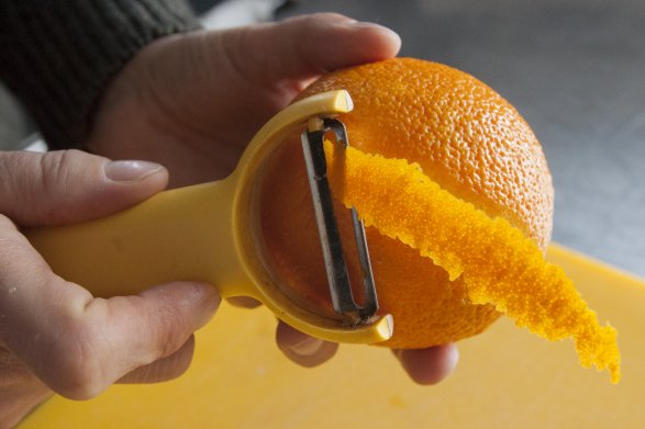 Obieranie pomarańczy ze skórki za pomocą żółtej obieraczki.