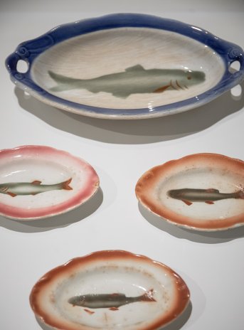 Cztery podłużne talerze z namalowaną na dnie długą rybą. Talerze różnią się trochę kształtem i kolorem.